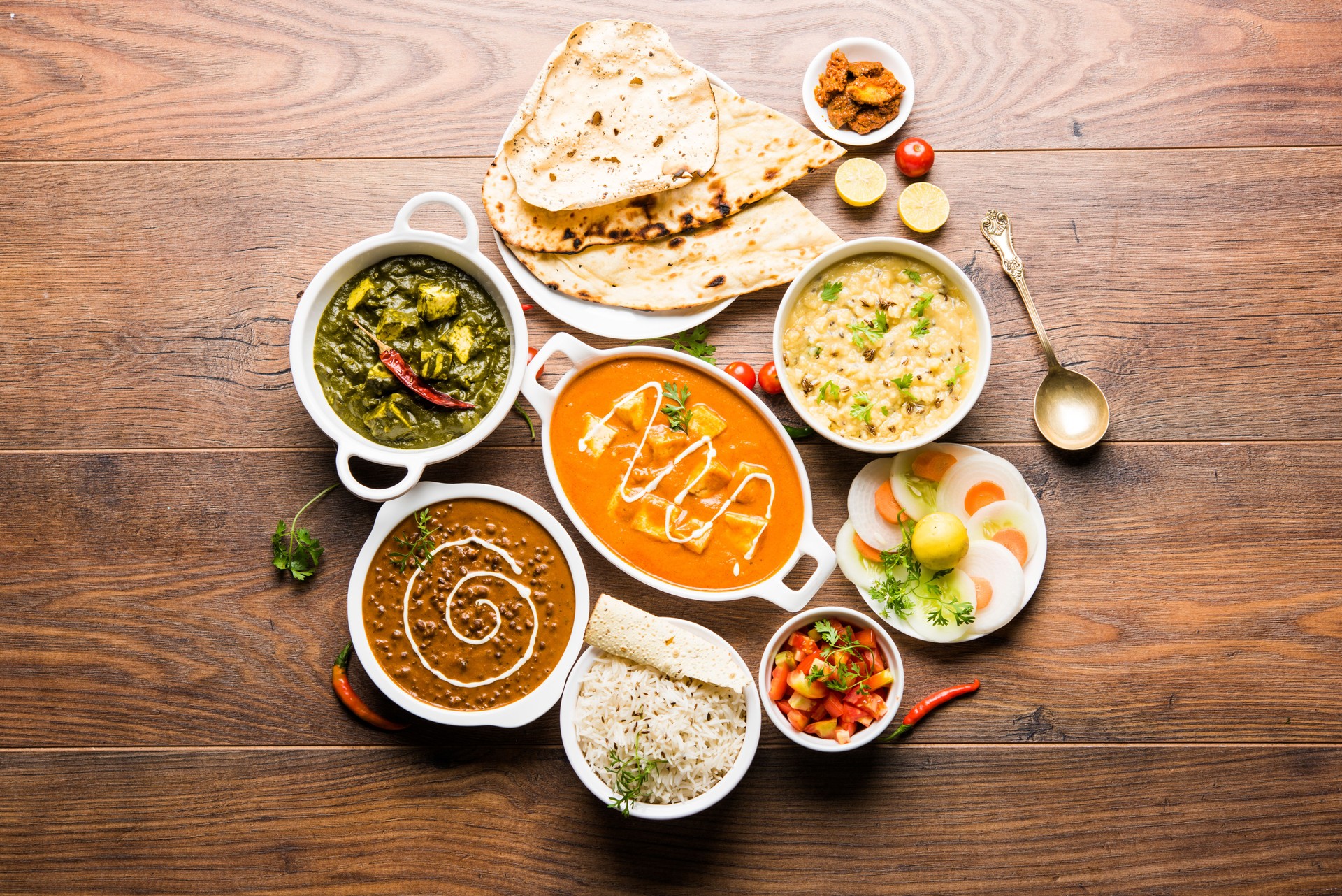Assorted indian food for lunch or dinner, rice, lentils, paneer, dal makhani, naan, chutney, spices over moody background. selective focus